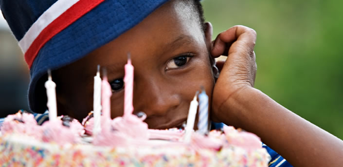 Kid in front of his birthday cake.