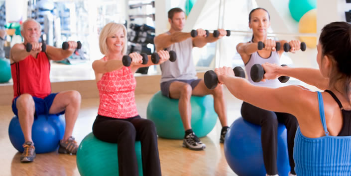 People working out in the gym with weights and exercise balls.